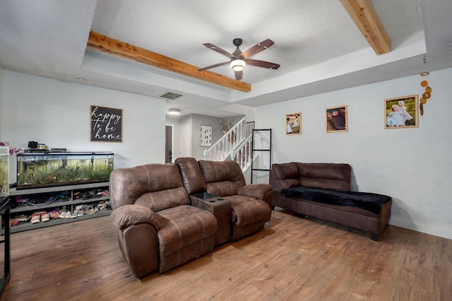 living room featuring visible vents, ceiling fan, beam ceiling, wood finished floors, and stairs