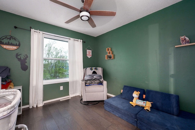 living area with ceiling fan, a textured ceiling, wood finished floors, and baseboards