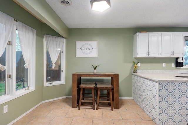 dining area featuring a textured ceiling, light tile patterned floors, baseboards, and visible vents