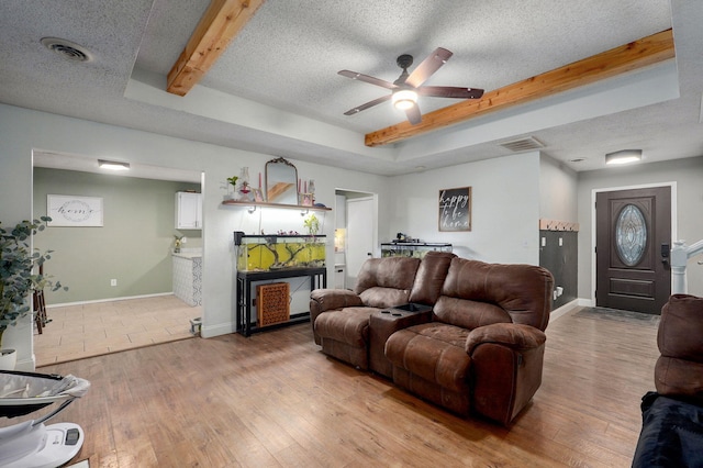 living area featuring light wood finished floors, visible vents, and a textured ceiling