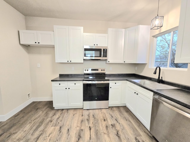 1511 W Lee St, Springfield, MO 65803 - kitchen with dark countertops, white cabinetry, a sink, and appliances with stainless steel finishes