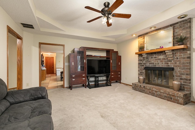 3740 W Glenwood Ct, Springfield, MO 65807 - living room featuring a ceiling fan, visible vents, a tray ceiling, a brick fireplace, and carpet