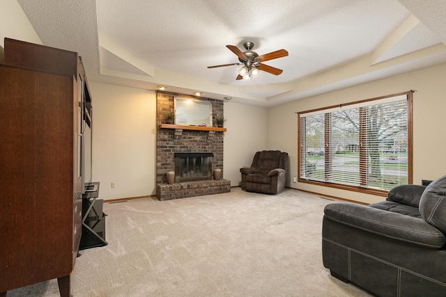 3740 W Glenwood Ct, Springfield, MO 65807 - living room featuring a raised ceiling, a ceiling fan, a fireplace, a textured ceiling, and light carpet