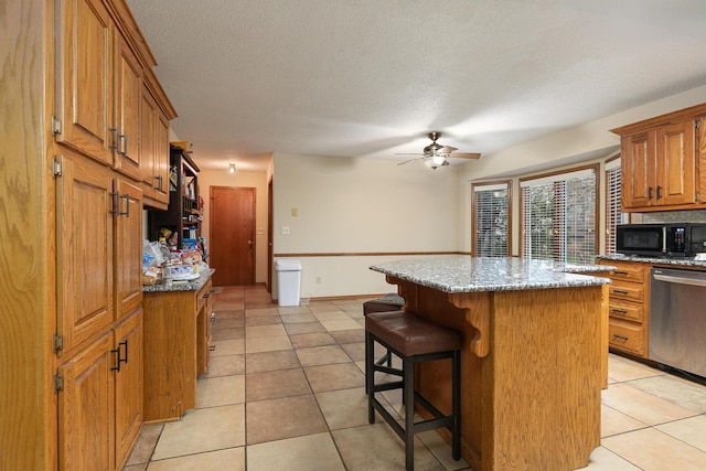 3740 W Glenwood Ct, Springfield, MO 65807 - kitchen with light tile patterned floors, ceiling fan, black microwave, light stone countertops, and stainless steel dishwasher