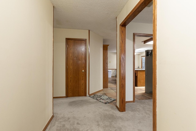 3740 W Glenwood Ct, Springfield, MO 65807 - hallway featuring tile patterned flooring, a textured ceiling, baseboards, and carpet floors
