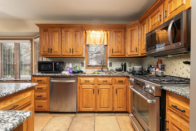 3740 W Glenwood Ct, Springfield, MO 65807 - kitchen with stainless steel appliances, light tile patterned floors, and brown cabinets