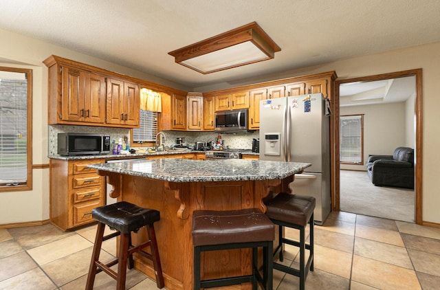 3740 W Glenwood Ct, Springfield, MO 65807 - kitchen with stainless steel appliances, a center island, backsplash, and a kitchen bar