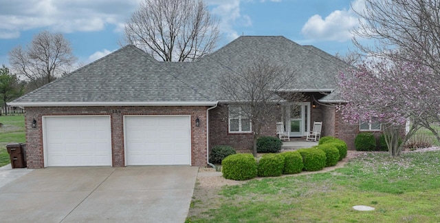 view of front of property with an attached garage, driveway, a front lawn, brick siding, and a shingled roof
