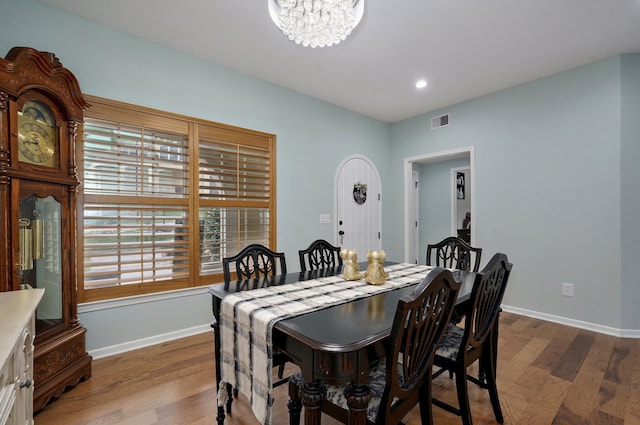 dining space featuring visible vents, baseboards, an inviting chandelier, and wood finished floors