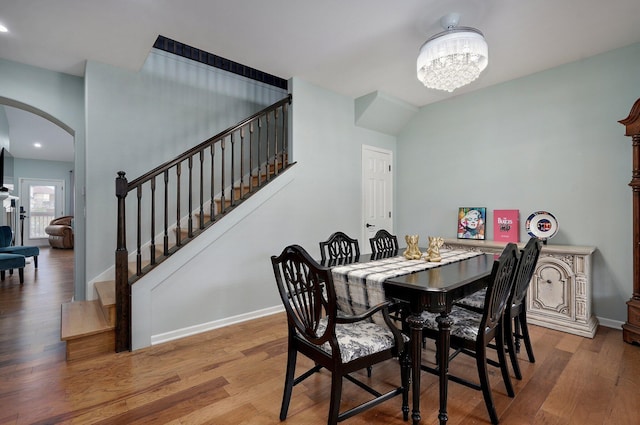 dining area with a chandelier, arched walkways, baseboards, and wood finished floors