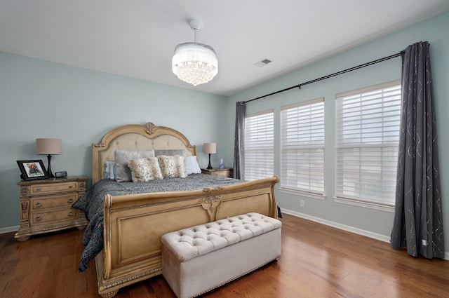 bedroom with a notable chandelier, dark wood-style flooring, baseboards, and visible vents