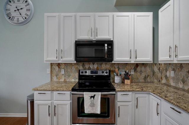 kitchen featuring backsplash, baseboards, white cabinetry, and electric stove