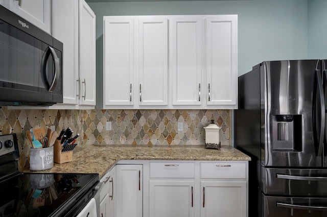 kitchen with stainless steel fridge, black microwave, white cabinets, range with electric cooktop, and decorative backsplash