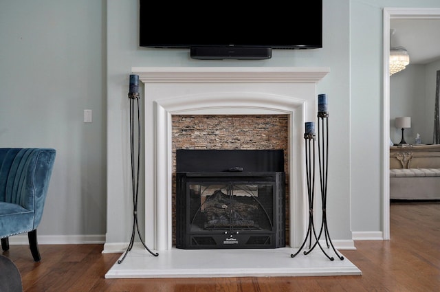 room details with baseboards, a fireplace with raised hearth, and wood finished floors