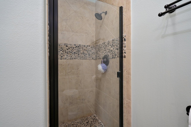 bathroom featuring a shower stall and a textured wall