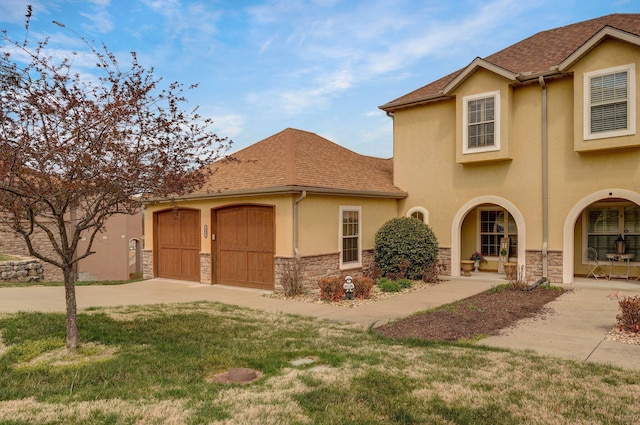view of front facade with driveway, stucco siding, stone siding, and a garage
