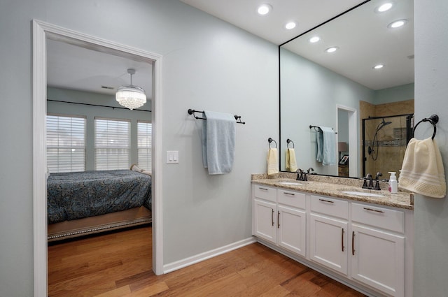 bathroom with ensuite bath, a sink, a stall shower, and wood finished floors