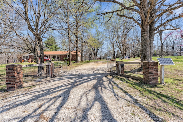 view of street with a gated entry, a gate, and gravel driveway
