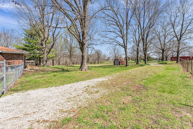 view of yard with a storage shed, an outbuilding, and fence