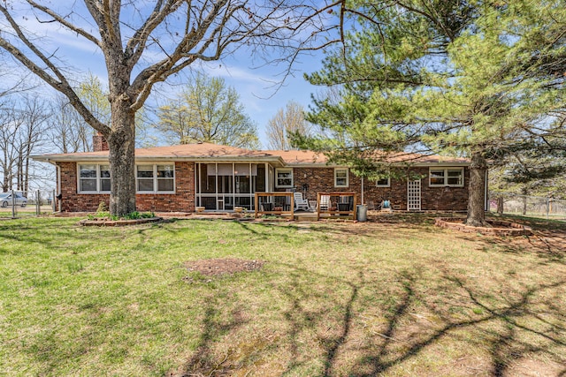 back of property featuring a sunroom, a lawn, a chimney, fence, and brick siding