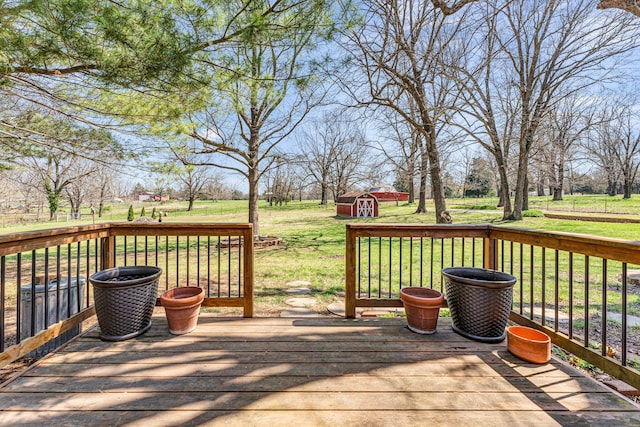 deck featuring a rural view, a storage shed, an outdoor structure, and a lawn