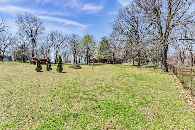 view of yard featuring an outdoor structure, fence, and an outdoor fire pit