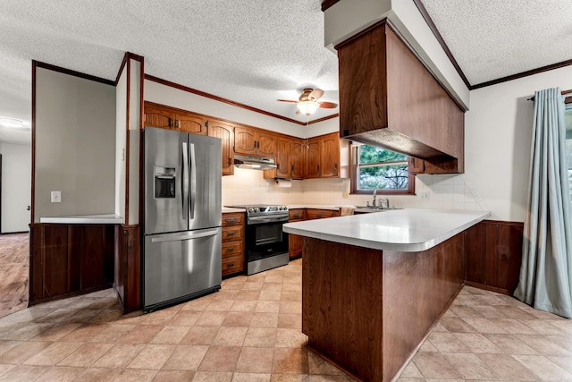 kitchen featuring ornamental molding, a peninsula, light countertops, under cabinet range hood, and appliances with stainless steel finishes