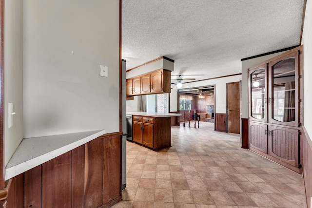 kitchen with ornamental molding, light countertops, ceiling fan, a textured ceiling, and wainscoting