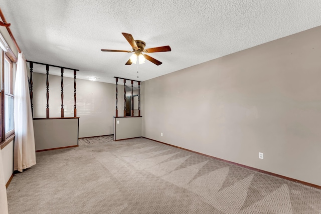 spare room with baseboards, a ceiling fan, light colored carpet, and a textured ceiling