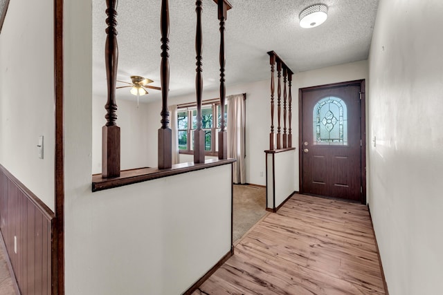 foyer with light wood-style flooring, a textured ceiling, and ceiling fan
