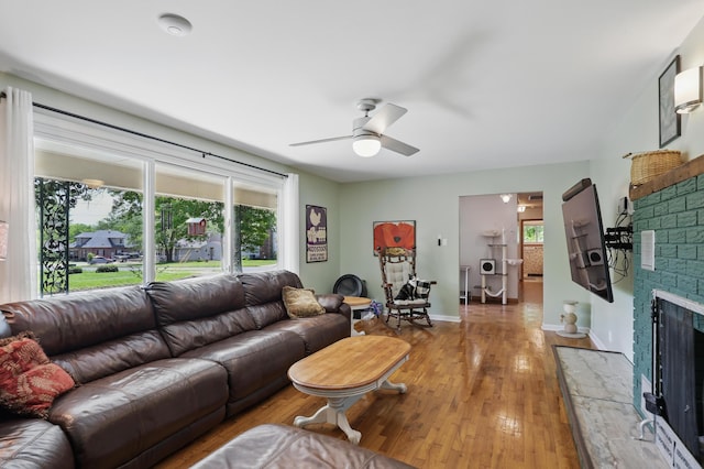 310 W Wishart Dr, Monett, MO 65708 - living area featuring a ceiling fan, a fireplace with raised hearth, light wood-style floors, and baseboards