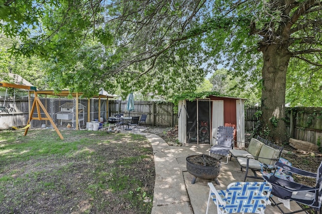 310 W Wishart Dr, Monett, MO 65708 - fenced backyard featuring an outbuilding, a storage shed, an outdoor fire pit, and a patio