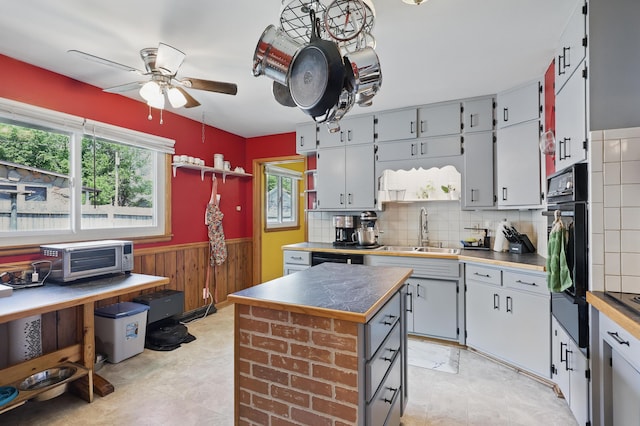 310 W Wishart Dr, Monett, MO 65708 - kitchen featuring a sink, ceiling fan, wainscoting, a kitchen island, and oven