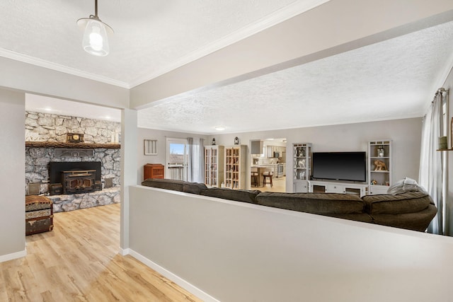 living room featuring baseboards, a textured ceiling, crown molding, a wood stove, and wood finished floors
