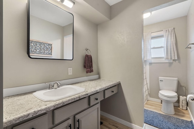 bathroom featuring a shower with shower curtain, vanity, baseboards, toilet, and wood finished floors