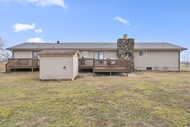back of property featuring a yard, a chimney, a wooden deck, and roof with shingles