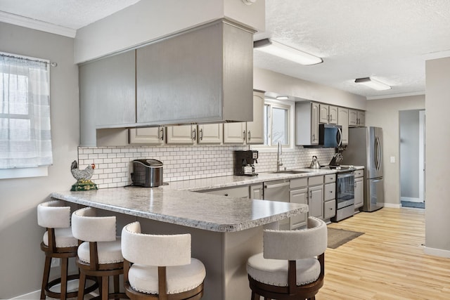 kitchen with a peninsula, a breakfast bar, light countertops, a sink, and stainless steel appliances