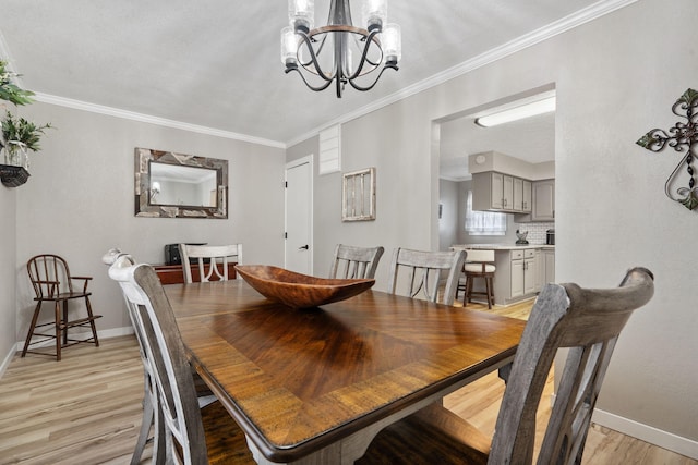 dining area with a chandelier, light wood-style floors, crown molding, and baseboards