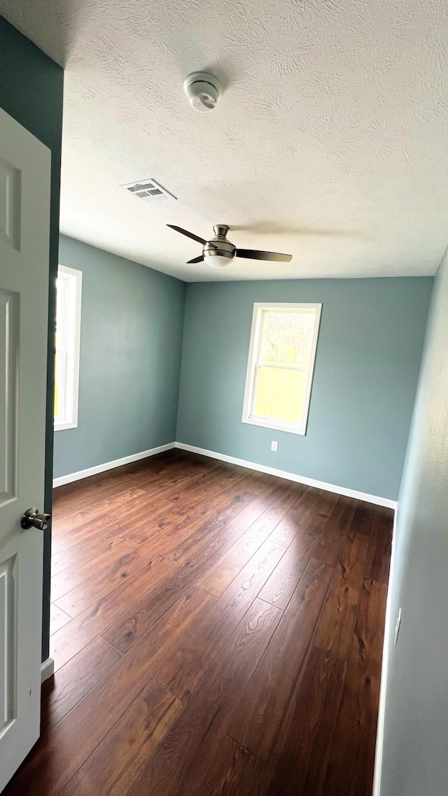 100 E Bond St, Monett, MO 65708 - unfurnished room with baseboards, dark wood-style floors, visible vents, and a ceiling fan