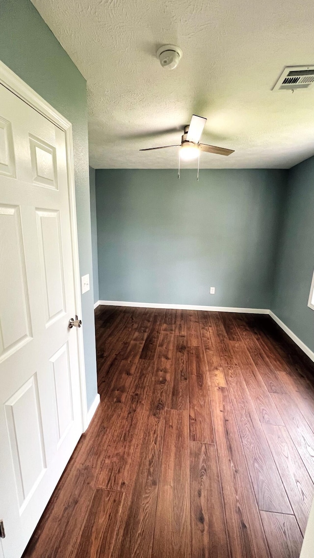 100 E Bond St, Monett, MO 65708 - unfurnished room with dark wood-style flooring, visible vents, baseboards, and a ceiling fan