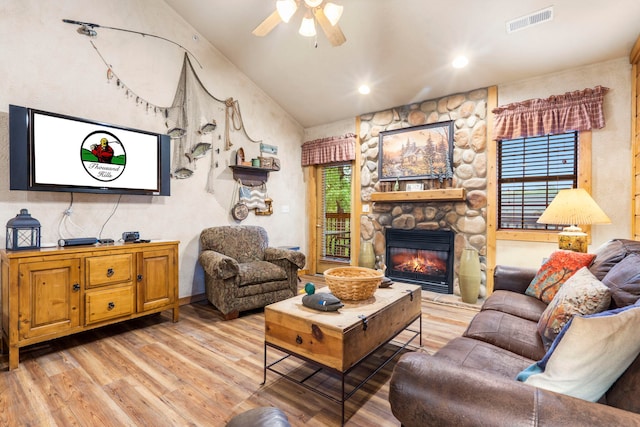 135 Rock Candy Ln, Branson, MO 65616 - living room with light wood-style floors, a ceiling fan, a stone fireplace, vaulted ceiling, and visible vents