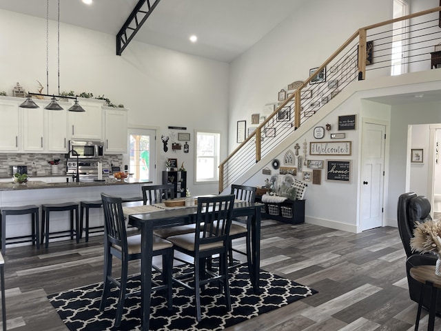 3826 S 77th Rd, Dunnegan, MO 65640 - dining space featuring dark wood finished floors, baseboards, a towering ceiling, and stairs