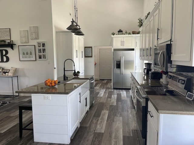 3826 S 77th Rd, Dunnegan, MO 65640 - kitchen with dark countertops, appliances with stainless steel finishes, white cabinetry, a towering ceiling, and dark wood-type flooring