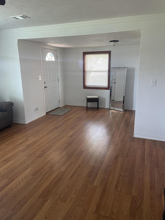 entryway featuring visible vents, baseboards, wood finished floors, and a textured ceiling