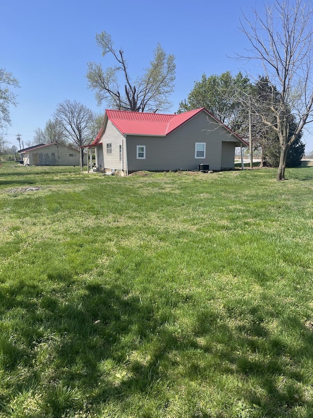 exterior space with metal roof and a lawn