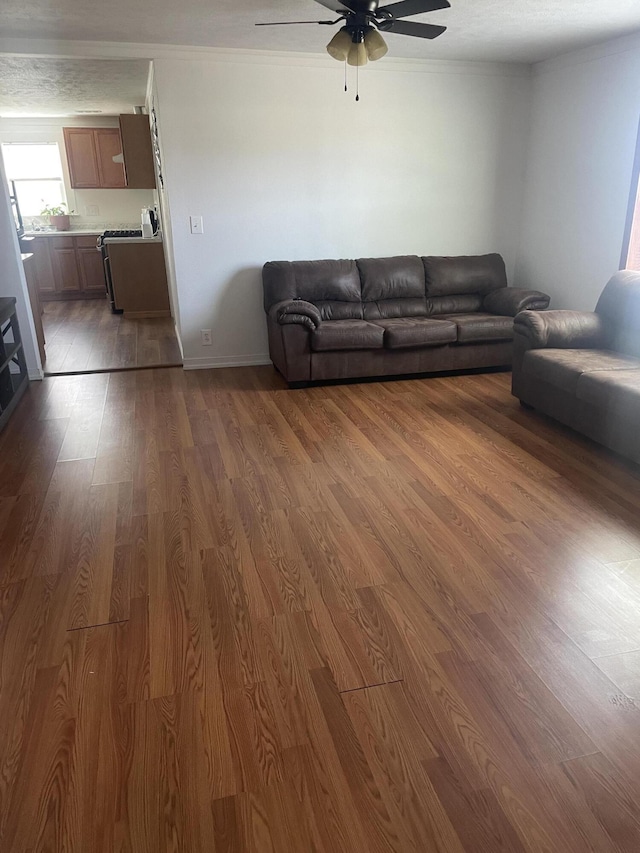 living area featuring wood finished floors, ornamental molding, and a ceiling fan