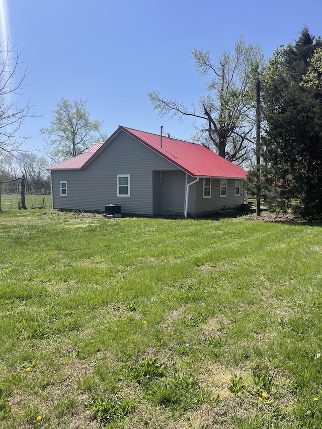 exterior space featuring a yard, metal roof, and central AC unit