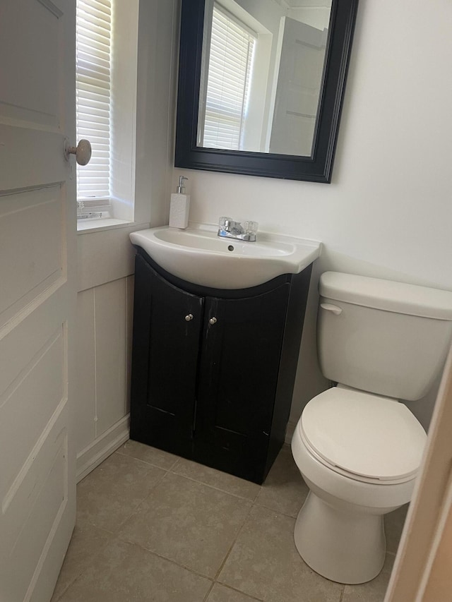 half bath with toilet, tile patterned floors, and vanity