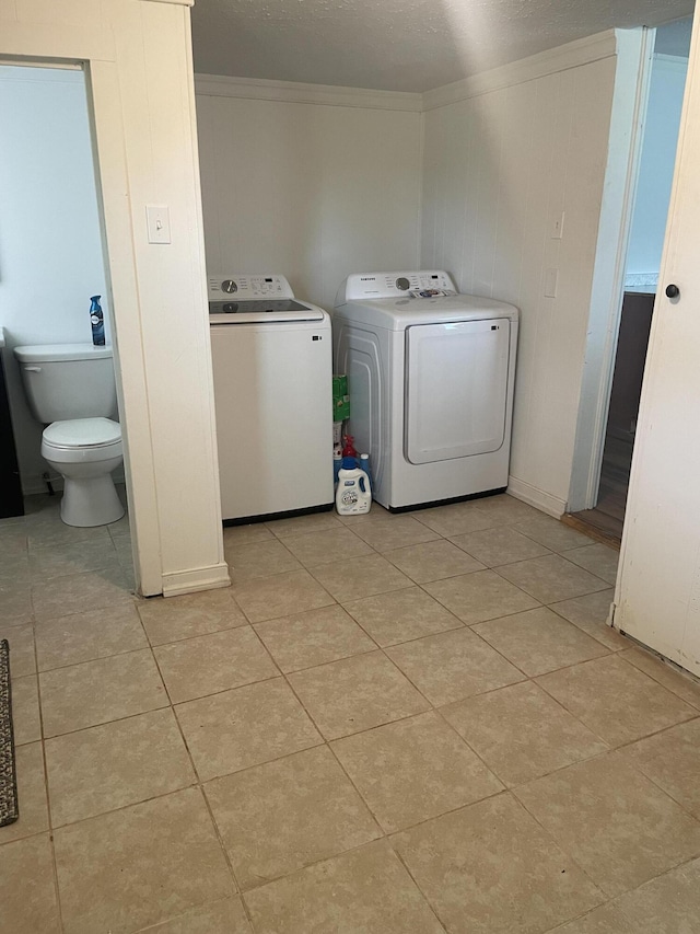 washroom with light tile patterned flooring, crown molding, laundry area, and washing machine and dryer