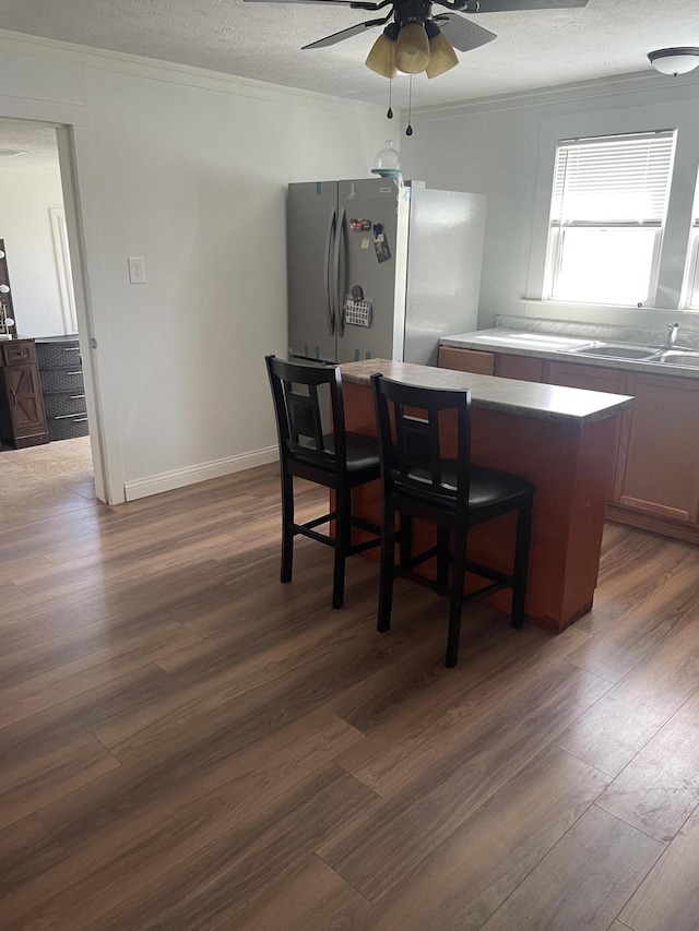kitchen with freestanding refrigerator, ceiling fan, dark wood-type flooring, a textured ceiling, and ornamental molding